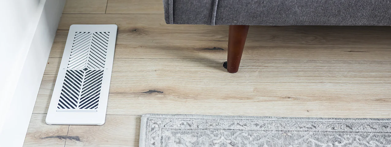 Flair Smart Vent installed on hardwood floor, showing modern vent grille design near living room rug.
