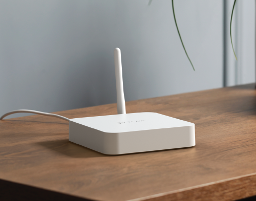 Flair Bridge smart home hub with antenna, used to connect Flair Smart Vents and Pucks, on a wooden table.
